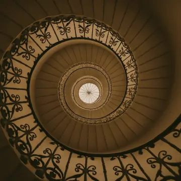 Jigsaw puzzle: Looking up an elegant spiral staircase with intricate wrought iron railings and a central skylight.