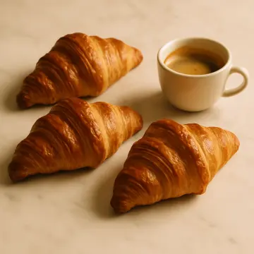 Jigsaw puzzle: Three golden-brown croissants are arranged around a white cup of espresso on a light surface.