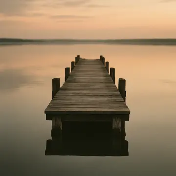 Jigsaw puzzle: A long wooden pier extends straight into tranquil water under a hazy, orange-toned sky.